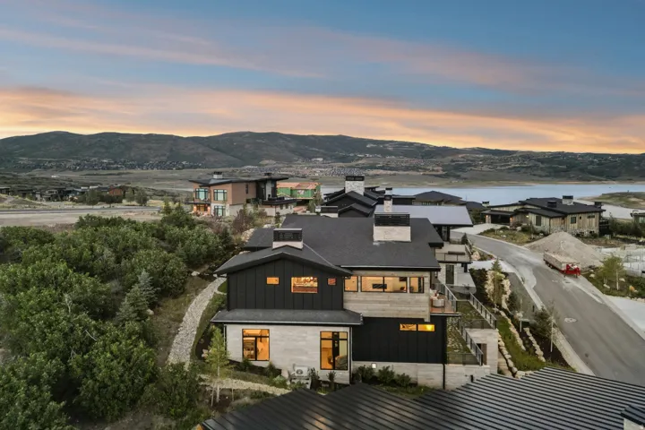 Multi-level residence featuring a dark metal roof, black siding, and stone accents