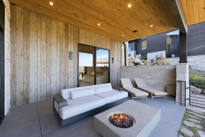 Covered patio featuring wood-paneled ceiling, recessed lighting, concrete flooring, and a built-in fire pit
