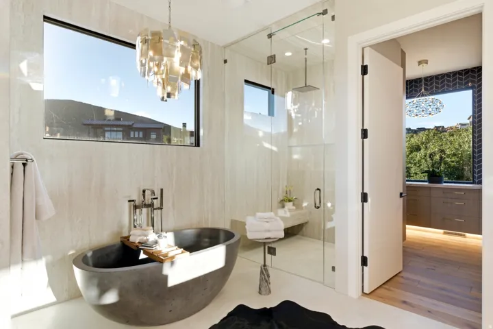 Freestanding soaking tub, glass-enclosed shower with a built-in bench, wall-mounted showerhead, and tile-finish walls