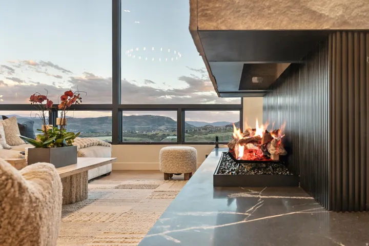 Full-height windows, contemporary fireplace with dark stone surround, ribbed paneling, stone hearth, and wood-finish flooring