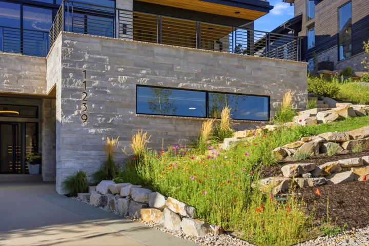 Stone facade with horizontal window, upper balcony, and tiered landscaping