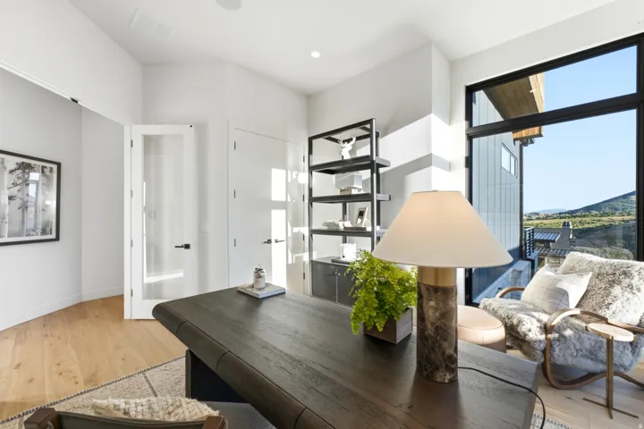 Hardwood-style flooring, a large window, a glass-paneled door, and a built-in shelving unit