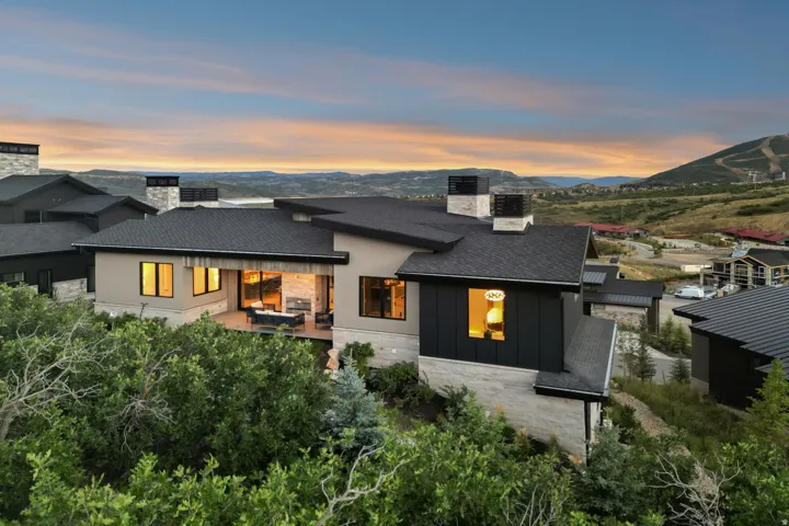 Modern architectural design with multiple rooflines, stone and stucco exterior, and a spacious covered patio