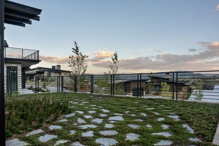 Stone paver patio with ground cover landscaping and a modern horizontal railing