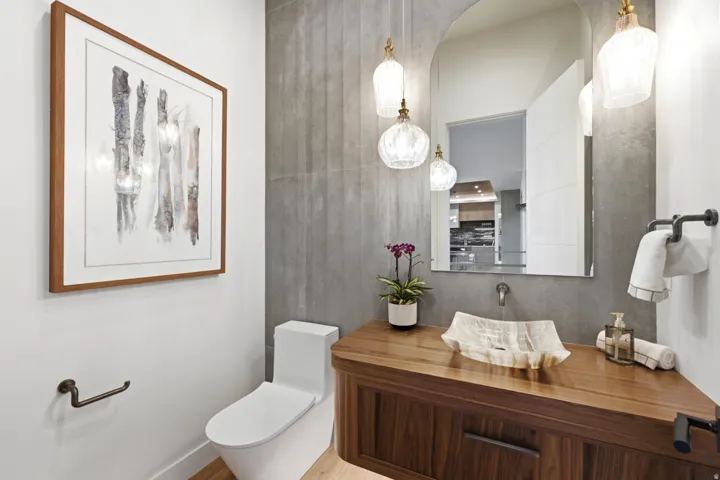 Walnut wood-finish vanity with an integrated vessel sink, wall-mounted faucet, and arched frameless mirror