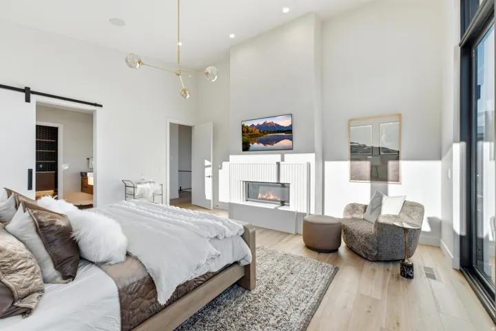 Integrated fireplace with a textured surround, recessed lighting, wood-finish flooring, and a barn door