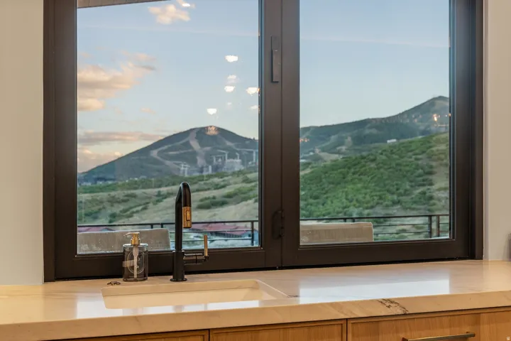 Integrated basin sink with a matte black and brass faucet, set into a stone countertop, with wood cabinetry