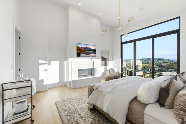 Vaulted ceiling, floor-to-ceiling windows, integrated fireplace, light wood-finish flooring, and recessed lighting