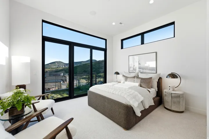 Expansive floor-to-ceiling windows with black frames, high ceilings, recessed lighting, and white walls