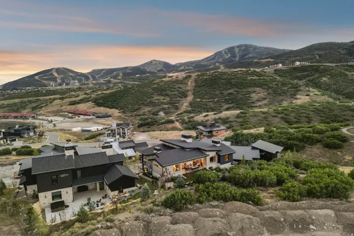 Modern architectural design with multiple structures, expansive outdoor living areas, and a multi-level layout, surrounded by natural landscaping