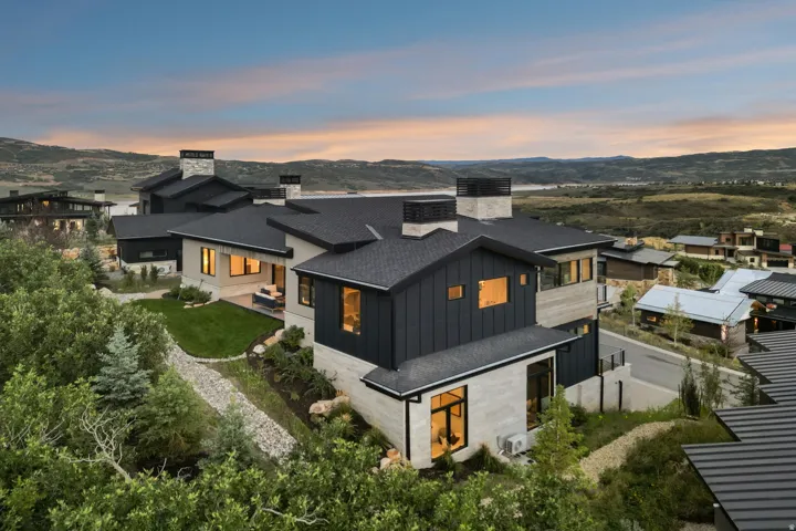 Multi-level residence featuring a dark metal roof and light-toned stone and dark vertical siding