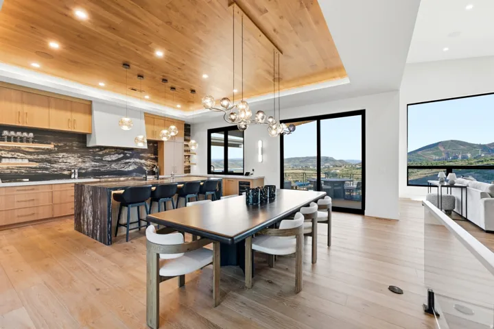 Spacious open-concept interior with wood-finish flooring, a kitchen island featuring a waterfall countertop, and custom cabinetry