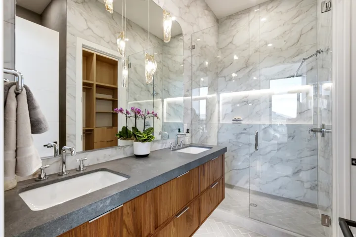 Floating wood-finish double vanity with undermount sinks and dark countertops