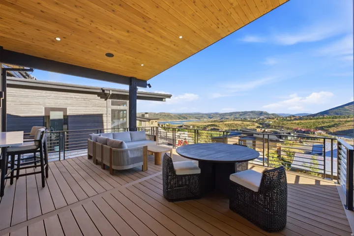 Expansive outdoor deck featuring wood-finish flooring, a wood-paneled ceiling with recessed lighting, and metal cable railing