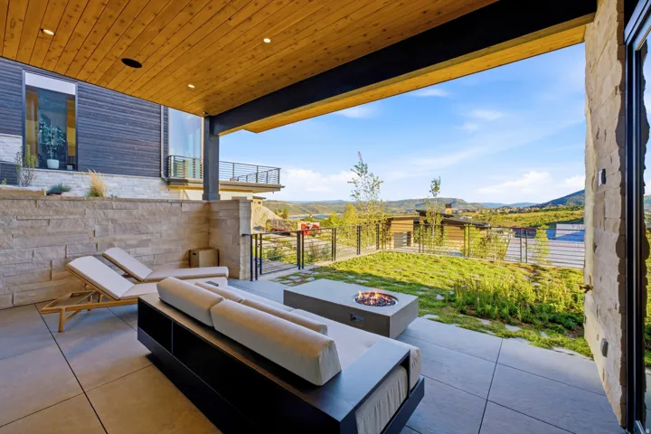 Expansive covered patio with wood-slat ceiling, recessed lighting, and large format tile flooring