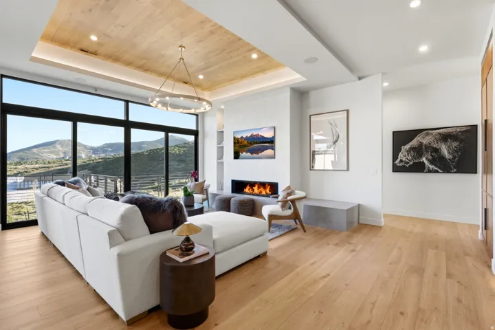 Expansive floor-to-ceiling windows, wood-finish flooring, a built-in linear fireplace, a wood-paneled ceiling, and recessed lighting