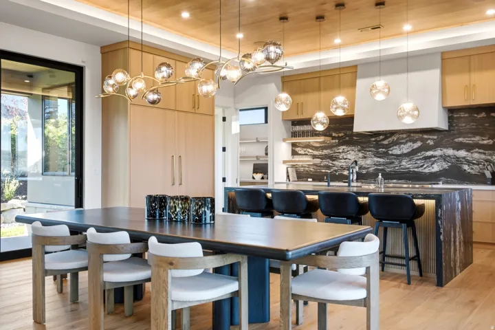 Wood-finish ceiling panels, wood-finish flooring, custom wood-finish cabinetry, full-height stone slab backsplash, and a black-framed sliding glass door