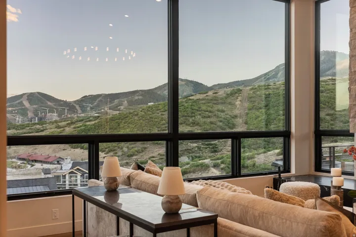 Expansive windows with mountain scenery, stone-clad pillar, and a built-in recessed ceiling light fixture