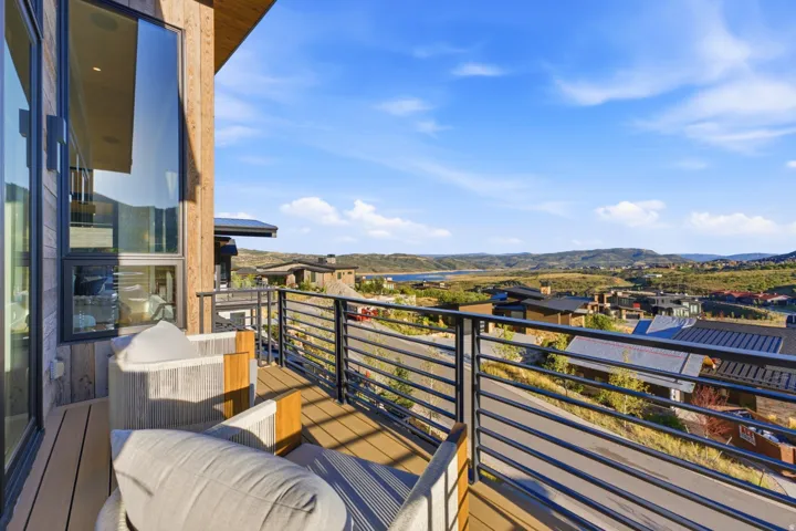 Balcony featuring composite decking, a horizontal bar railing, wood-paneled exterior siding, and large windows