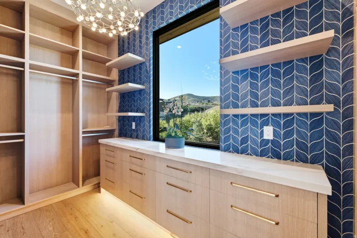 Built-in cabinetry with light wood-finish, light wood-finish flooring, and a contemporary chandelier