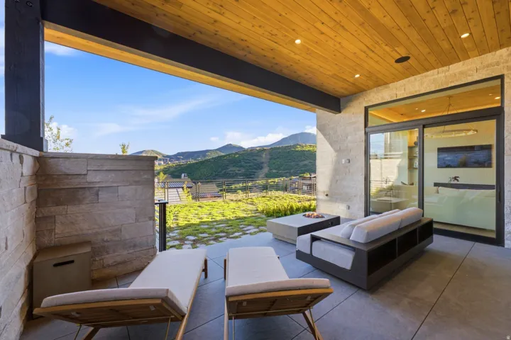 Covered patio with a wood-plank ceiling, recessed lighting, and stone veneer accent walls