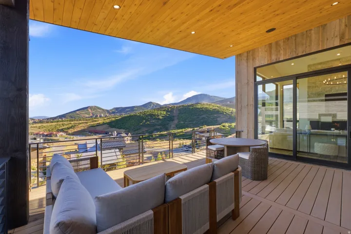 Expansive covered deck featuring a wood-finish ceiling, recessed lighting, and a sliding glass door