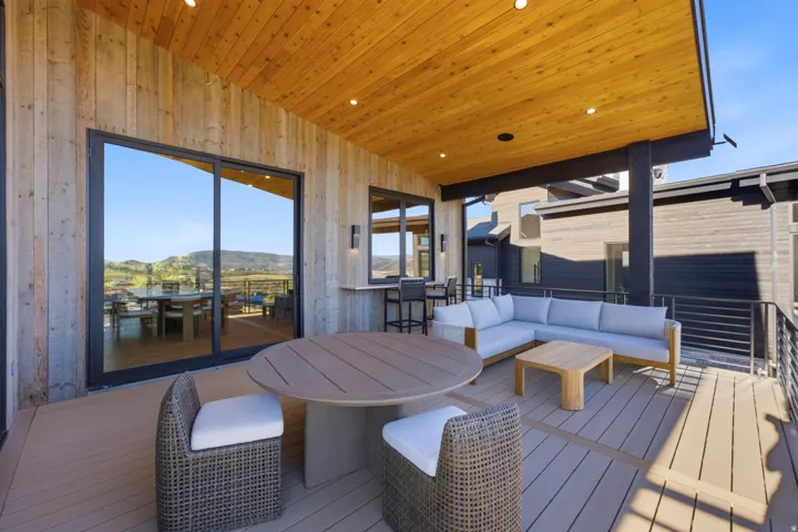 Expansive outdoor deck featuring wood-finish flooring, a wood-paneled ceiling with recessed lighting, and a built-in bar