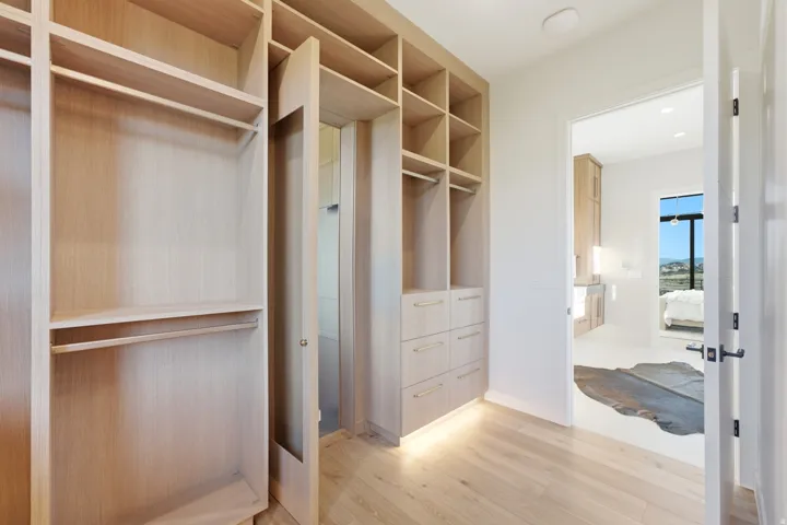 Custom closet system with integrated shelving and drawers, wood-finish flooring, and recessed ceiling lighting