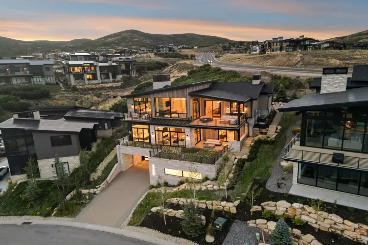 Modern exterior with extensive glass fenestration, multiple outdoor terraces, integrated garage, and stone accent walls