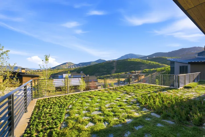 Outdoor terrace with integrated groundcover and stone pavers, bordered by horizontal slat railings and expansive mountain scenery