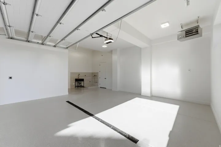 Attached garage with a utility sink, light-colored flooring, and overhead lighting