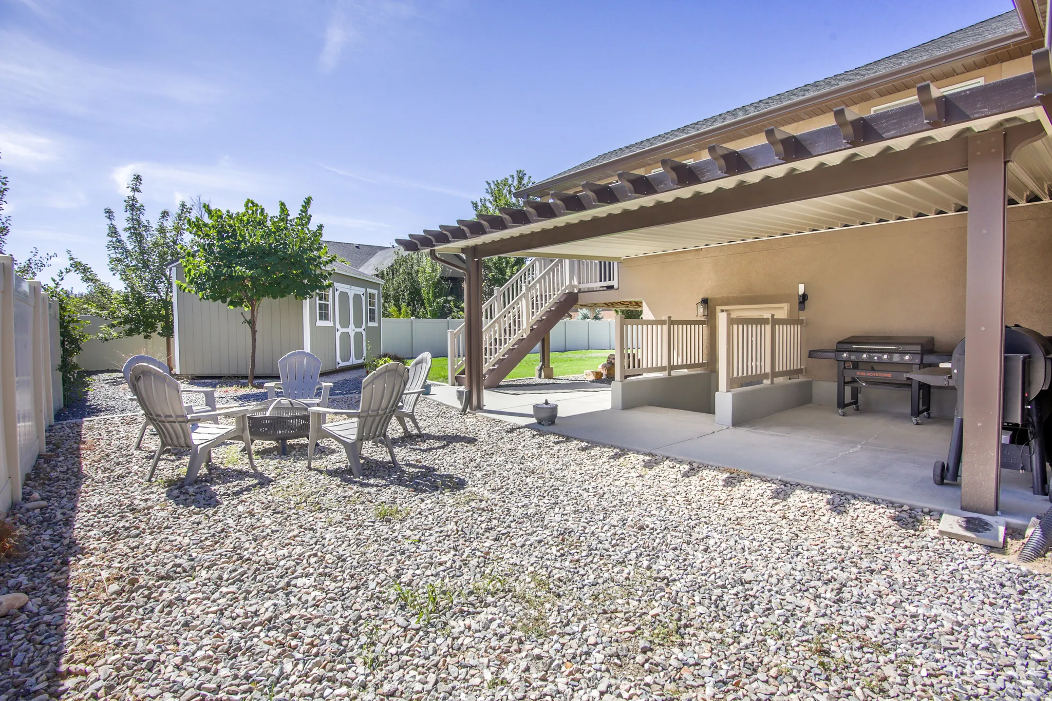 Expansive backyard featuring a covered patio, built-in staircase, and a detached storage shed