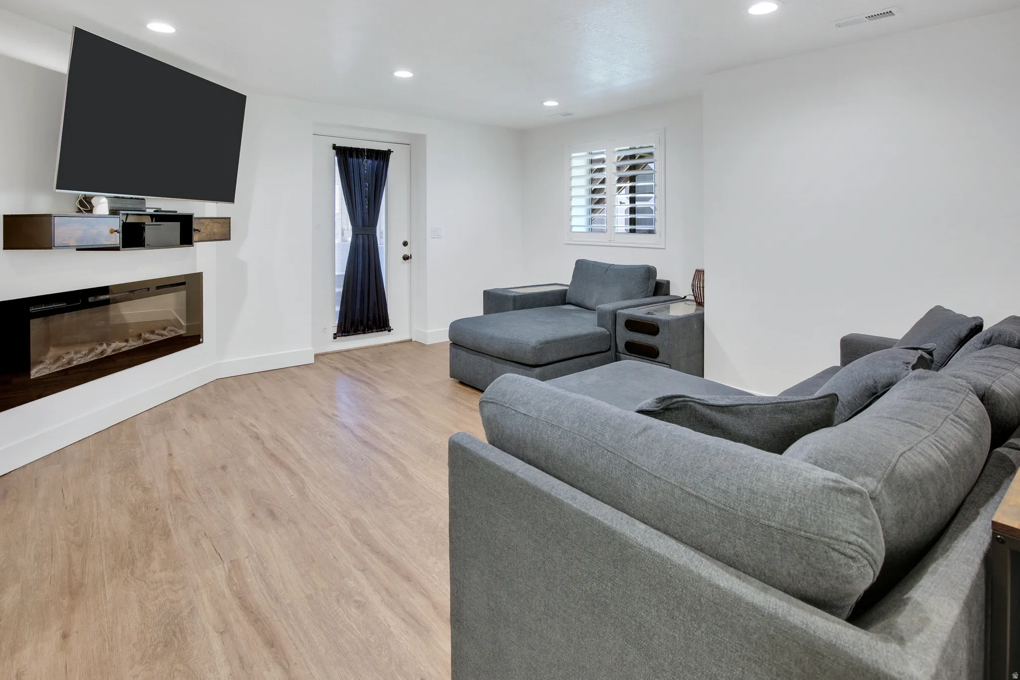 Wood-finish flooring, built-in fireplace, recessed lighting, and a window with plantation shutters