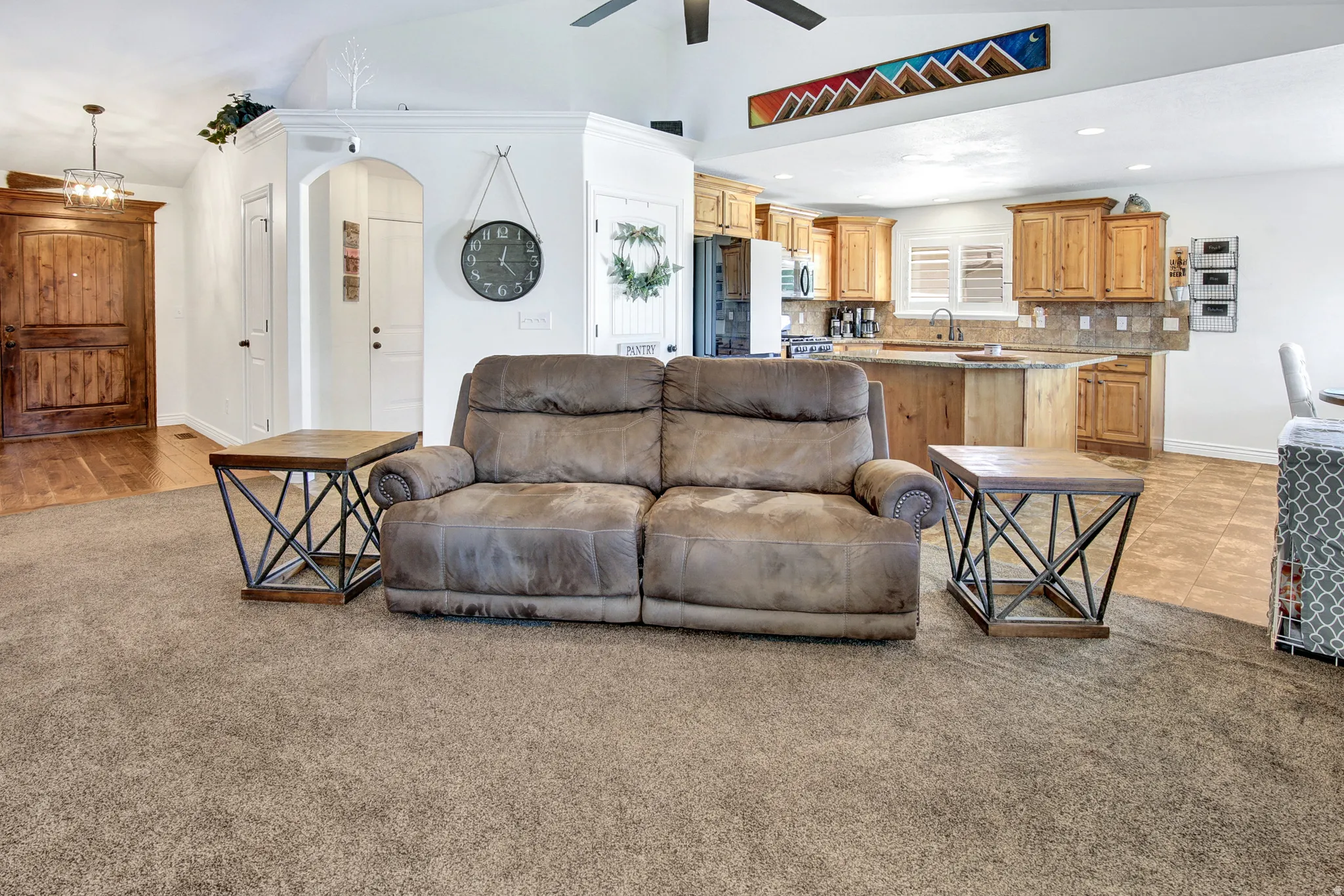 Open-concept living space featuring vaulted ceilings, recessed lighting, and a kitchen with wood cabinetry and an island