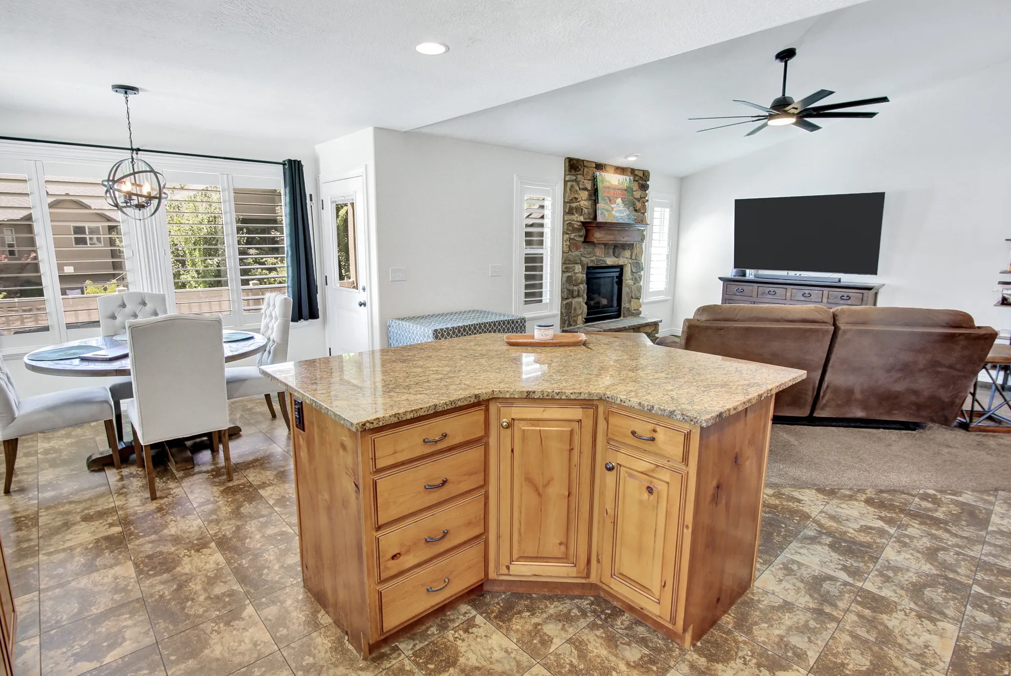 Kitchen island with granite countertop, recessed lighting, stone fireplace, ceiling fan, and tiled flooring