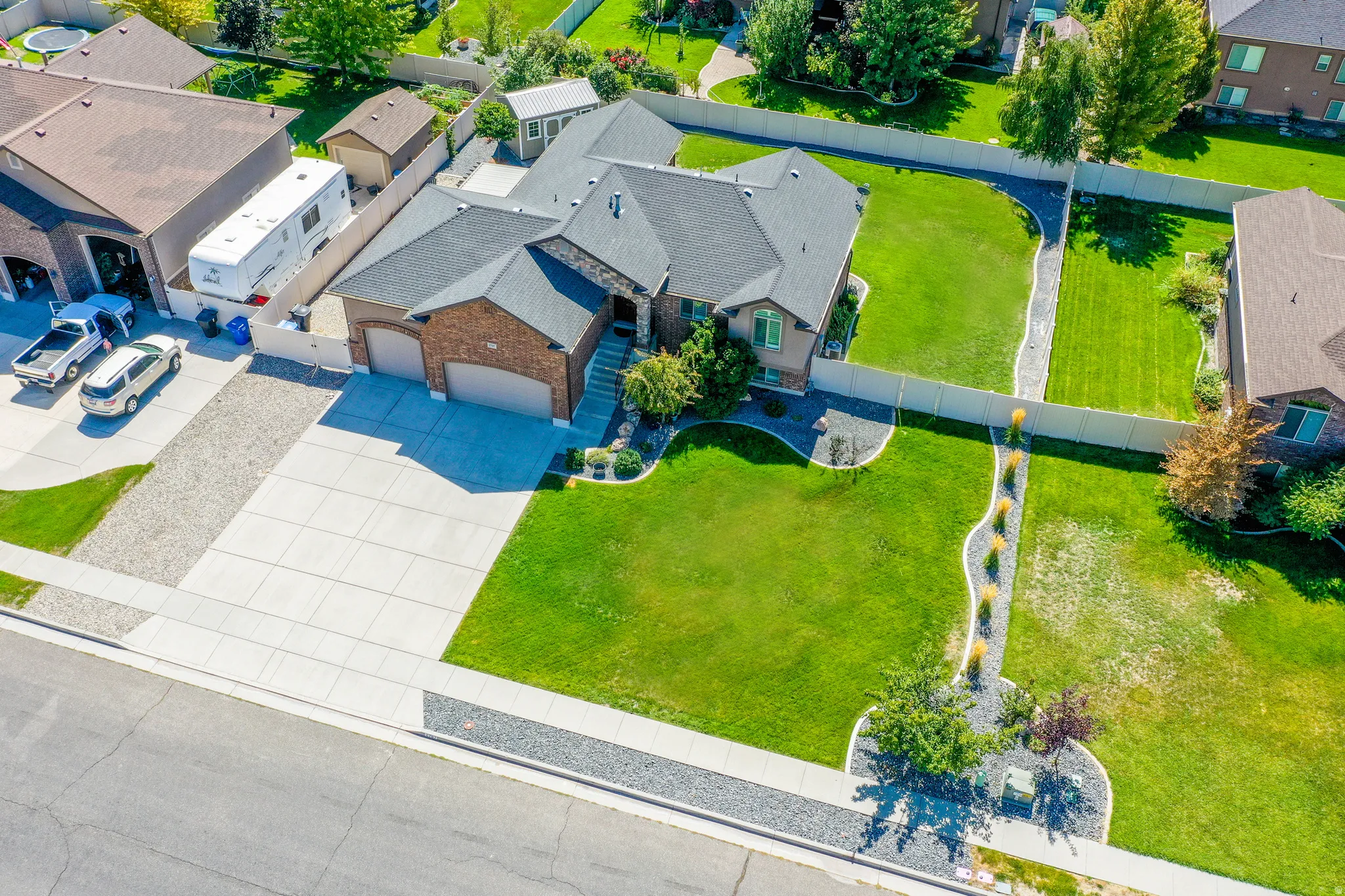 Brick exterior, attached two-car garage, mature landscaping, concrete driveway, and a fenced rear yard