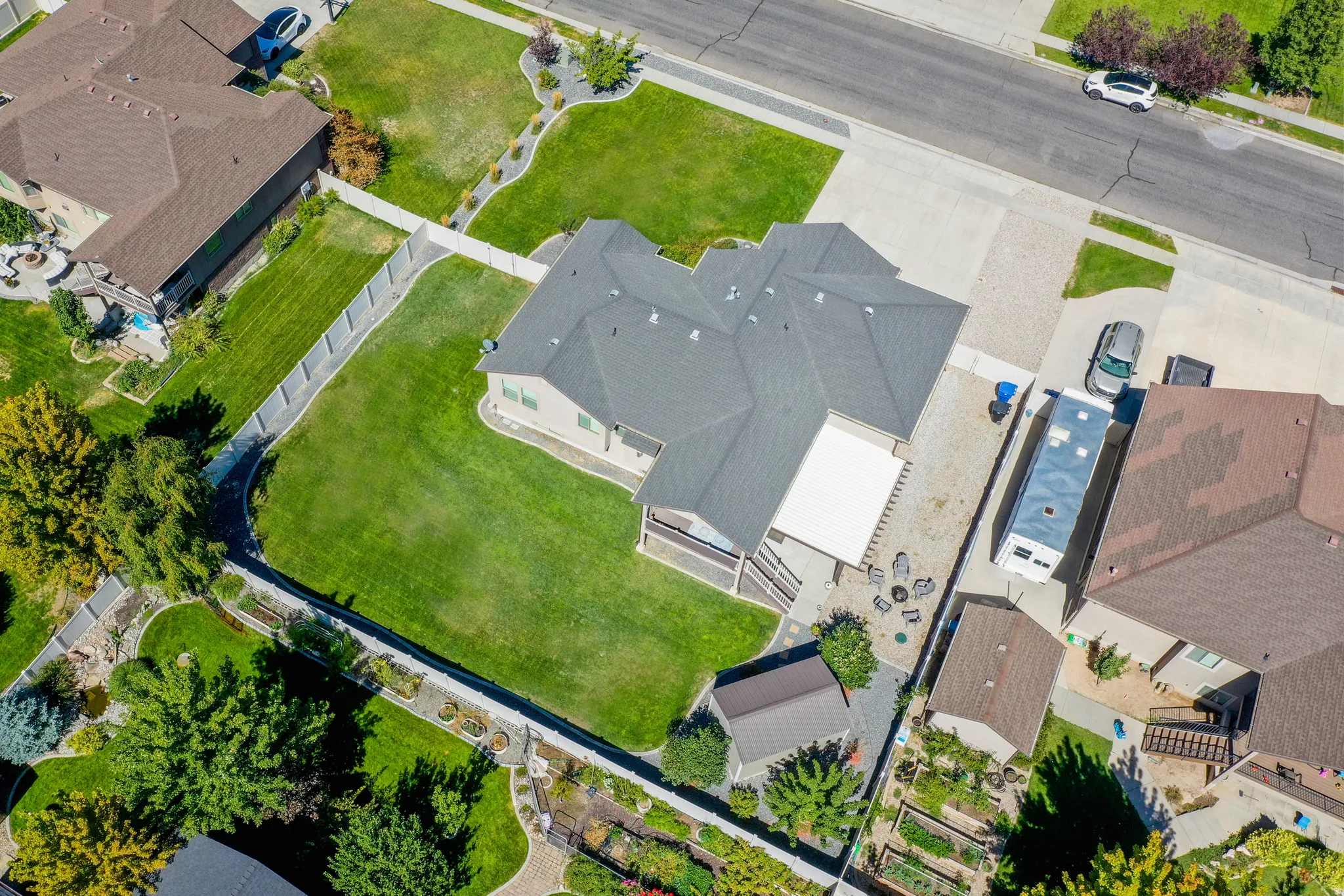Expansive property featuring a well-maintained lawn, privacy fencing, and multiple mature trees