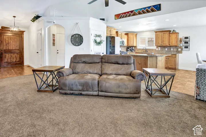 Open-concept living space featuring vaulted ceilings, recessed lighting, and a kitchen with wood cabinetry and an island