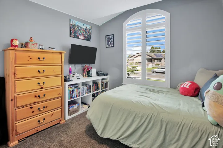 Arched window with plantation shutters, wall-mounted television, and built-in shelving
