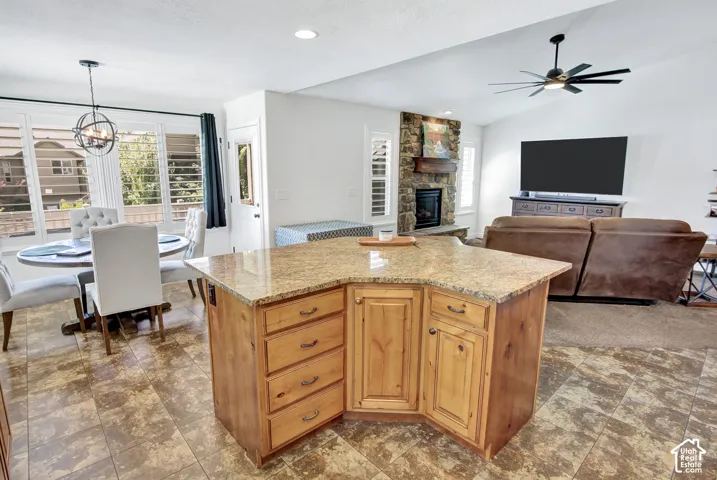 Kitchen island with granite countertop, recessed lighting, stone fireplace, ceiling fan, and tiled flooring