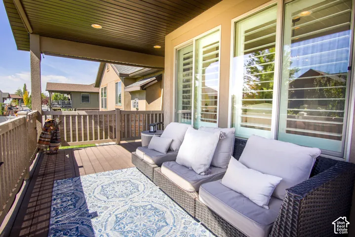 Covered outdoor patio with a composite deck surface, white sliding glass doors, and white interior plantation shutters