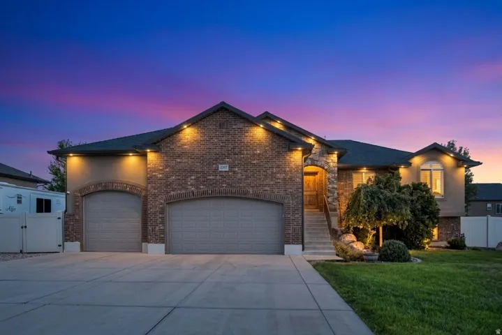 Brick and stucco facade with stone accents, arched garage doors, and an extended driveway