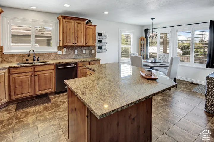 Hardwood cabinetry with stone countertops, tile backsplash, and integrated sink