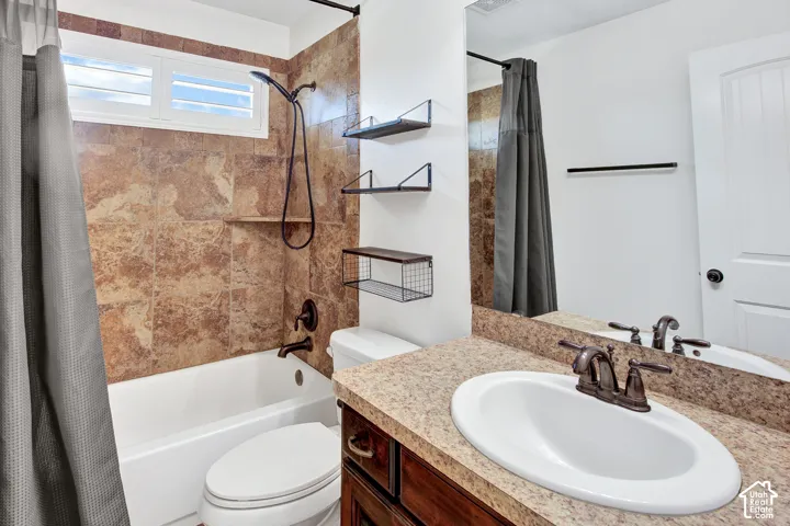 Built-in bathtub with a shower head, stone-finish wall tile, and a window with white shutters