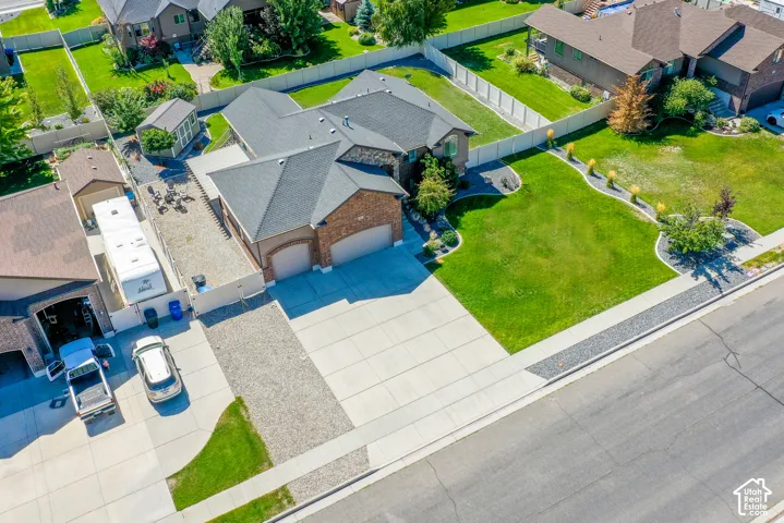 Expansive concrete driveway, attached two-car garage, mature landscaping, and an additional gravel parking area