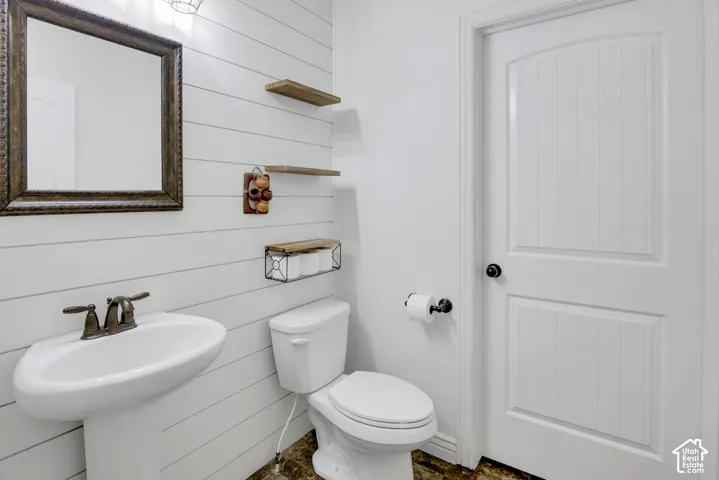 Pedestal sink with bronze-finish faucet, framed wall mirror, shiplap wall paneling, and a panel-style door
