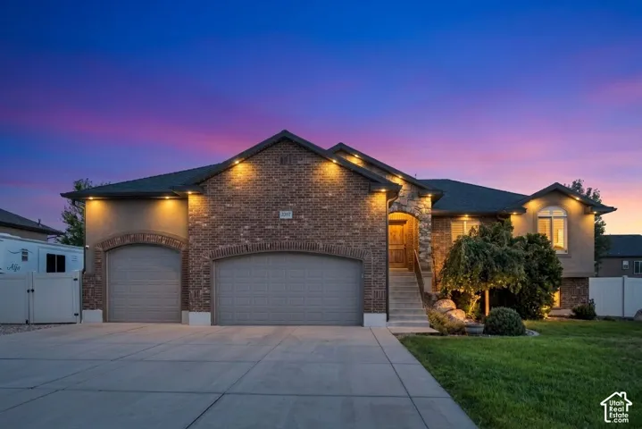Brick and stucco facade with stone accents, arched garage doors, and an extended driveway