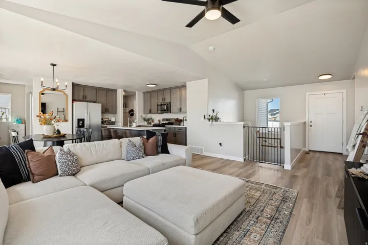 Vaulted ceiling with a ceiling fan, wood-finish flooring, recessed lighting, and a kitchen featuring grey cabinetry