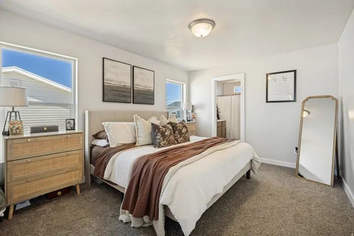Recessed ceiling light fixture, two large windows, neutral-toned walls, and carpet flooring