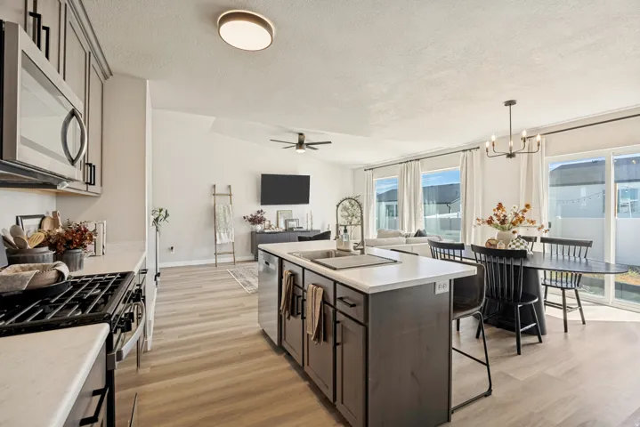 Contemporary kitchen with stainless steel appliances, kitchen island with seating, pendant lighting, wood-finish flooring, and sliding glass doors